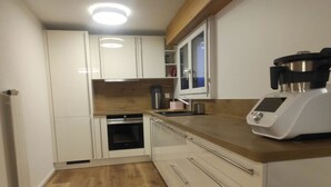 Una cucina moderna con mobili bianchi, un piano di lavoro in legno e un forno integrato.