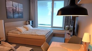 Une chambre d’hôtel équipée d’un lit, d’une table de chevet, d’une lampe, d’une chaise et offrant une vue sur l’extérieur.