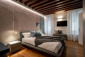 A modern bedroom with a bed, bedside tables, a TV, and a window with curtains.