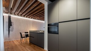 A modern kitchen with wooden beams, a built-in island, and a refrigerator. - Sant'Angelo Apartment by Wonderful Italy (Venice)