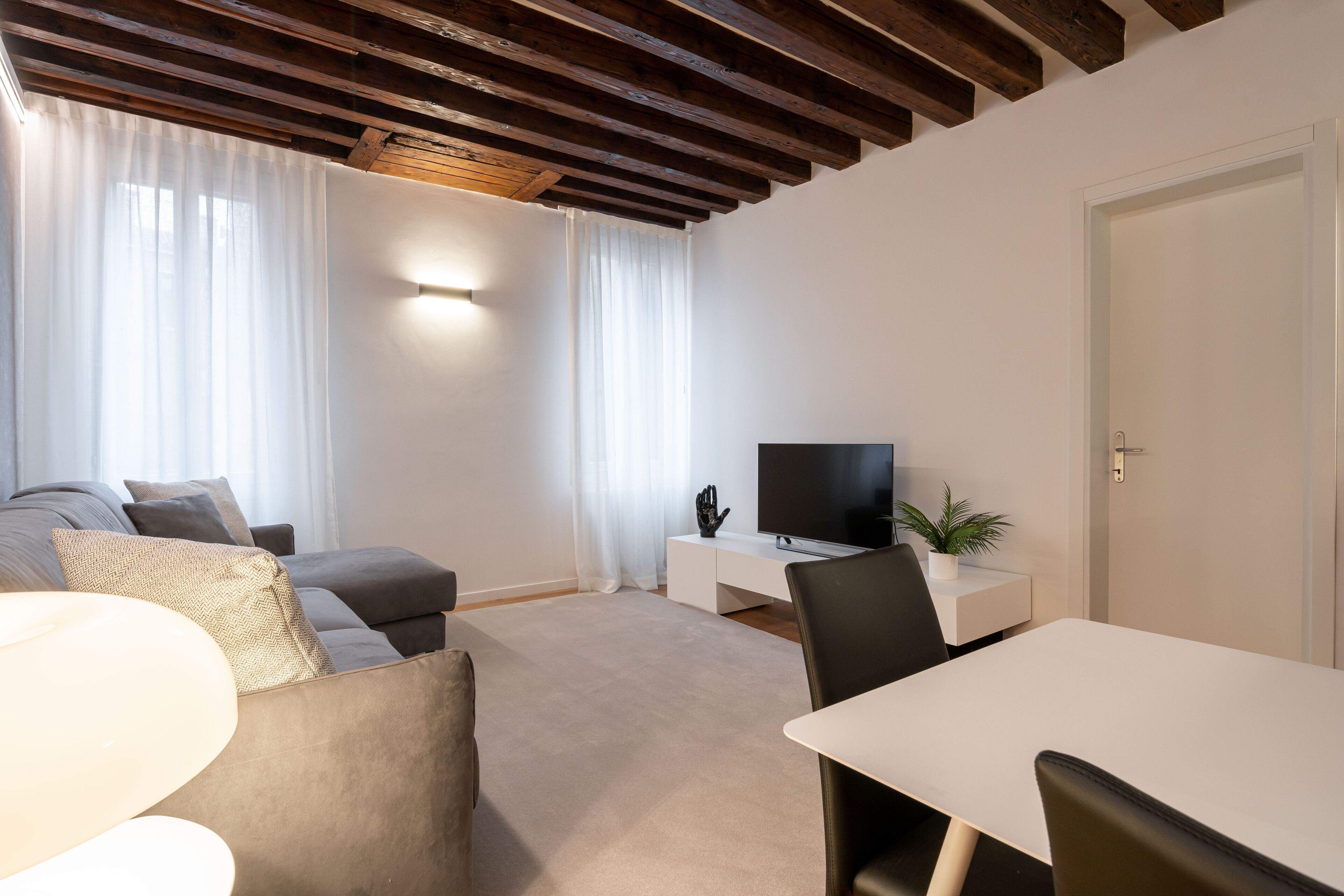 Uma sala de estar moderna com sofá, televisão, mesa de jantar e um armário branco.