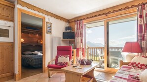 Una stanza accogliente con un letto, una poltrona rossa, un tavolo in legno e un balcone con vista.