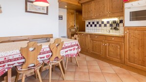 Una cucina con mobili in legno, zoccolo paraschizzi piastrellato e zona pranzo con tavolo apparecchiato per quattro.
