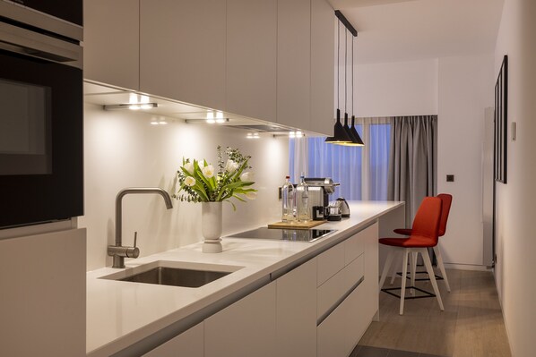 Cocina moderna con isla integrada, electrodomésticos de acero inoxidable y una silla roja.