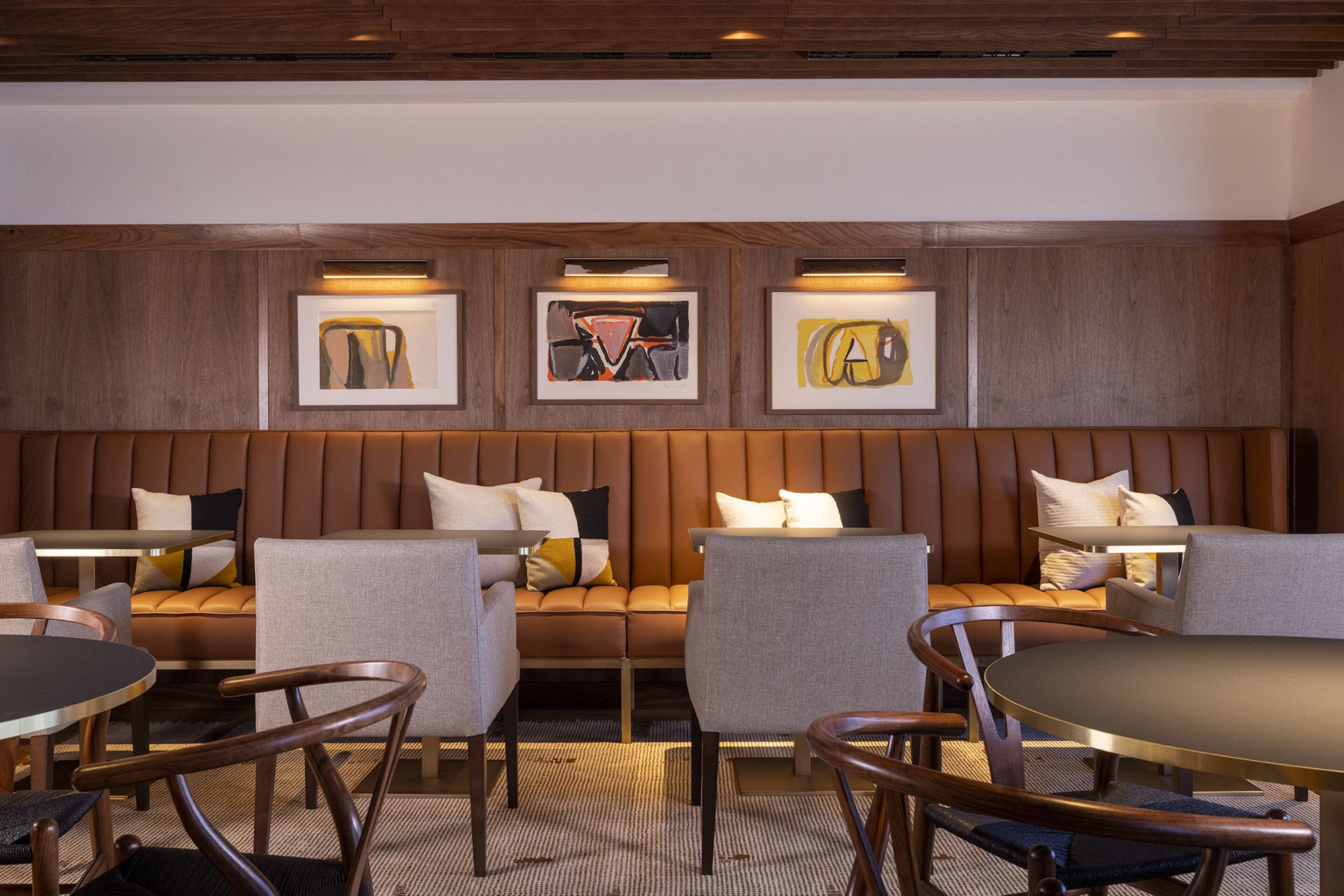 A modern hotel lobby with a seating area, a dining table, and artwork on the wall.
