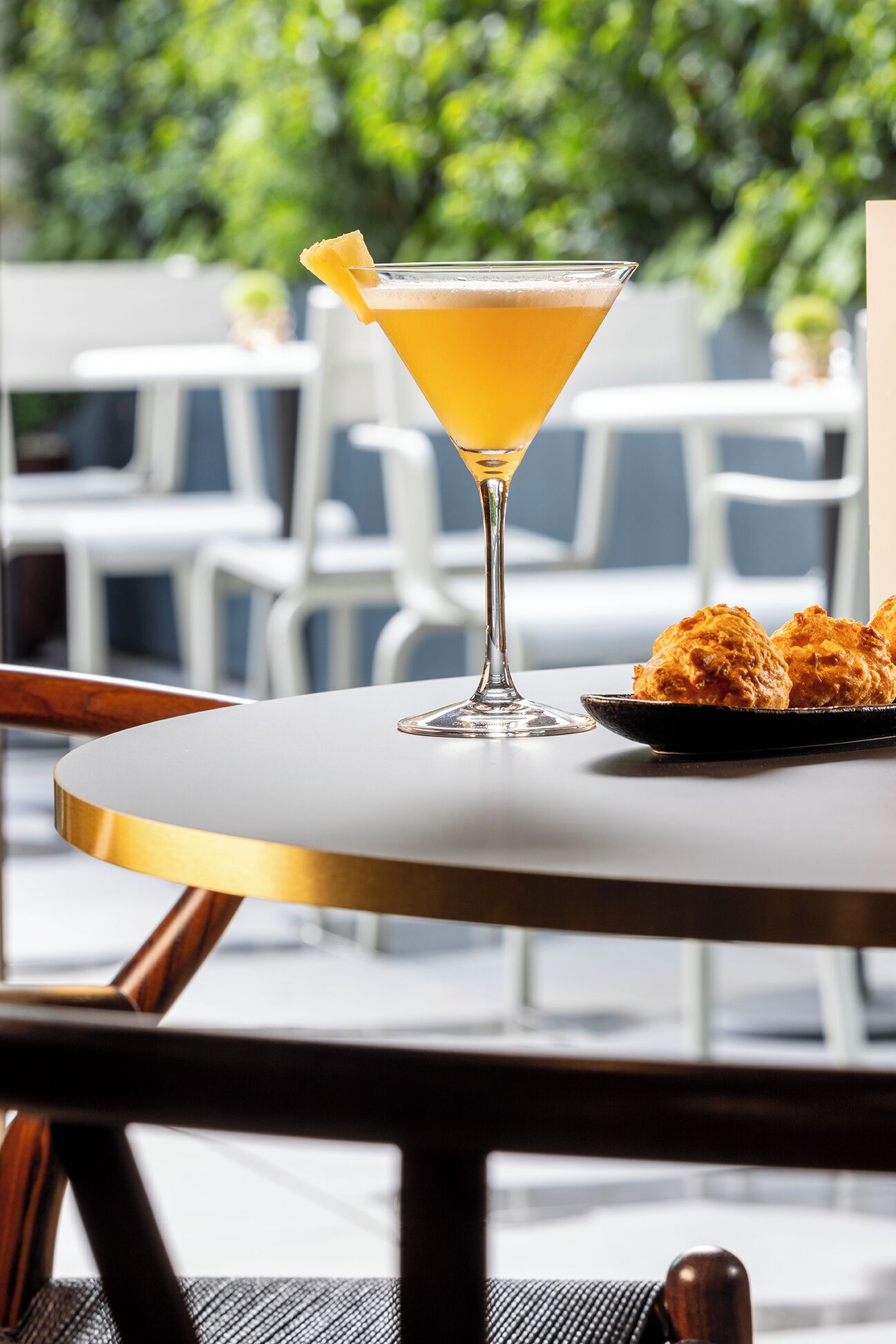 Una copa de martini con una rodaja de limón sobre una mesa redonda con un borde blanco y dorado.