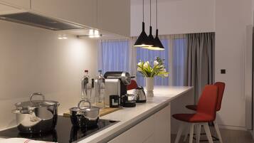 A modern kitchen with a central island, a coffee machine, and a red chair.