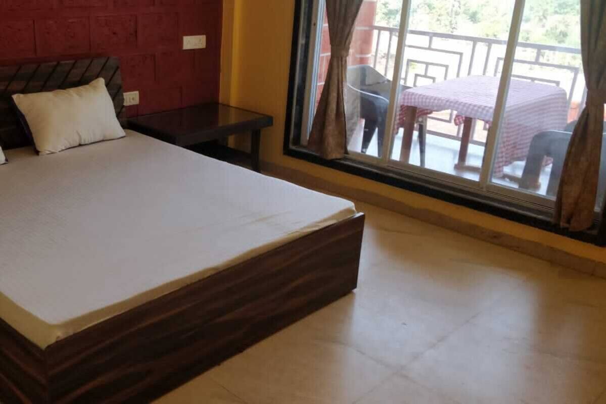 A bed with a wooden headboard, two pillows, and a view of an outdoor patio with a table and chairs.