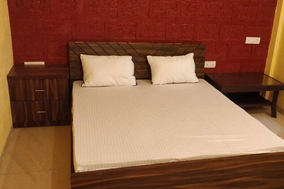 A bed with a wooden frame and a white mattress, two pillows, a nightstand, and a small table.