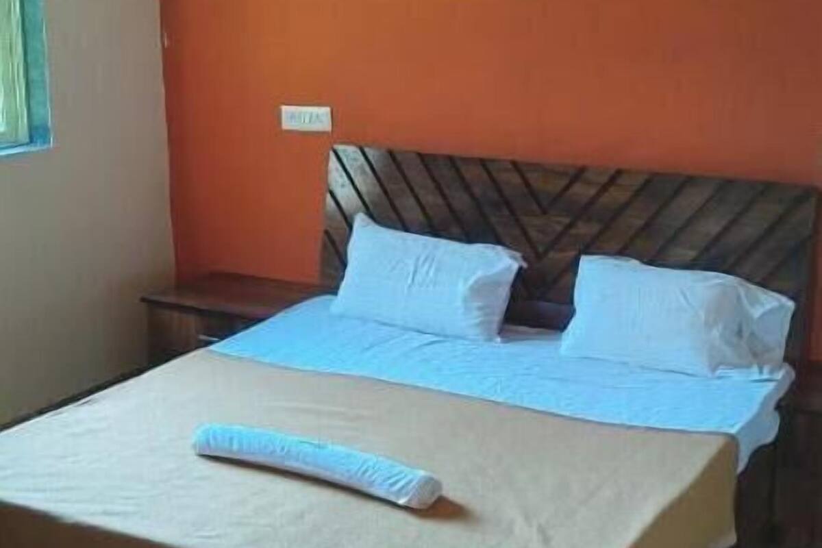 A single bed with a wooden headboard, a ceiling fan, and a wooden floor.