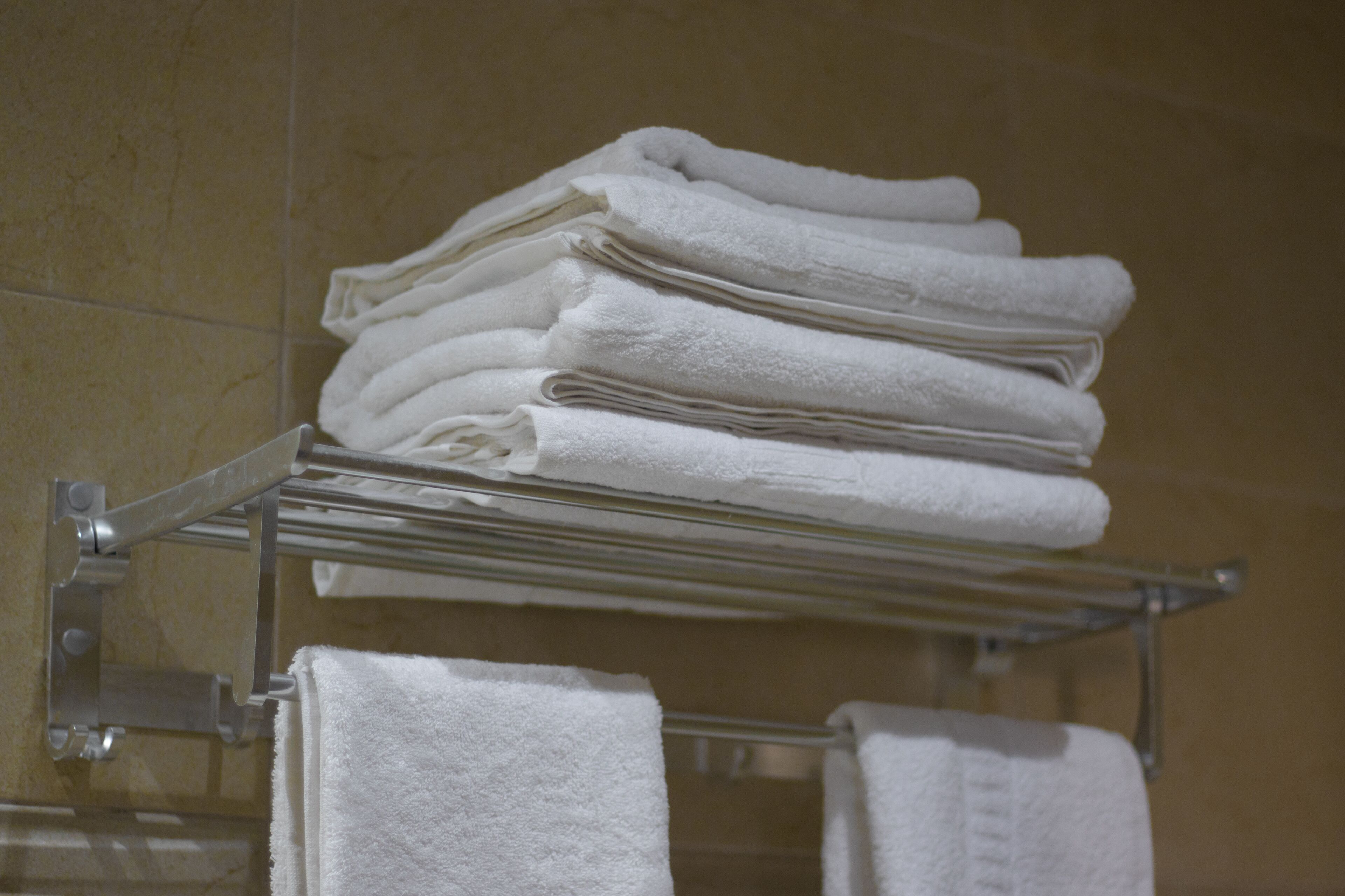 A stack of white towels on a metal rack in a bathroom.