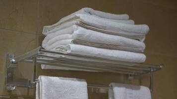 A stack of white towels on a metal rack in a bathroom.