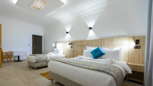 Ein modernes Hotelzimmer mit zwei Betten, einem Holzkopfende und einem kleinen Schreibtisch mit Stuhl.