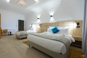Une chambre d’hôtel moderne avec deux lits, une tête de lit en bois et un petit bureau avec une chaise.