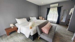 Et moderne soveværelse med en stor seng, en grå sofa og et lille natbord.
