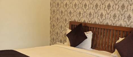 A neatly made bed with a wooden frame, white bedding, and a brown quilt.