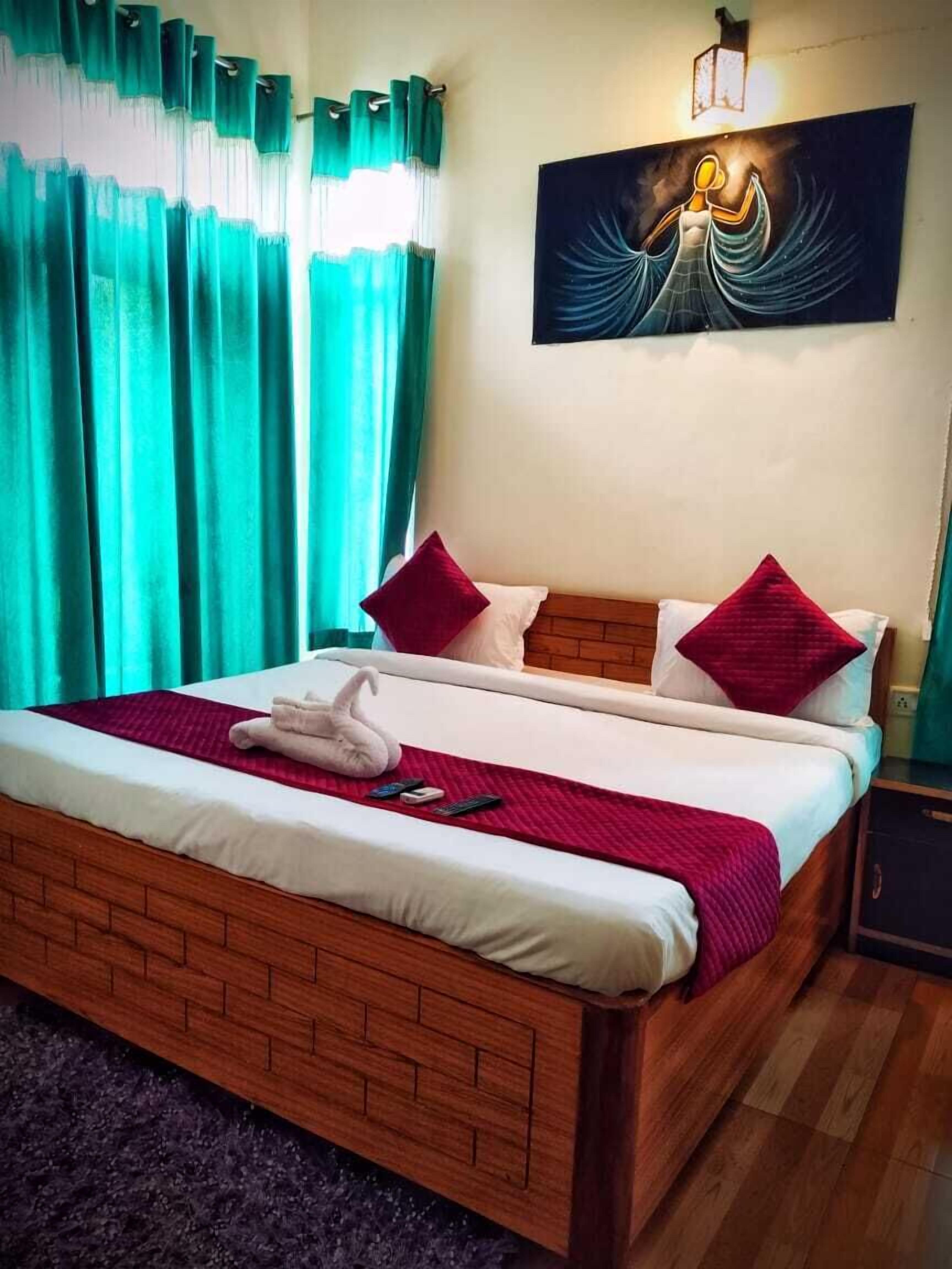 A neatly made bed with a white comforter, red pillows, and a red blanket.