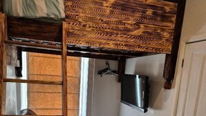 A compact room with a bunk bed, a sofa, a television mounted on the wall, and a radiator. - Alexander Hotel (Blackpool)