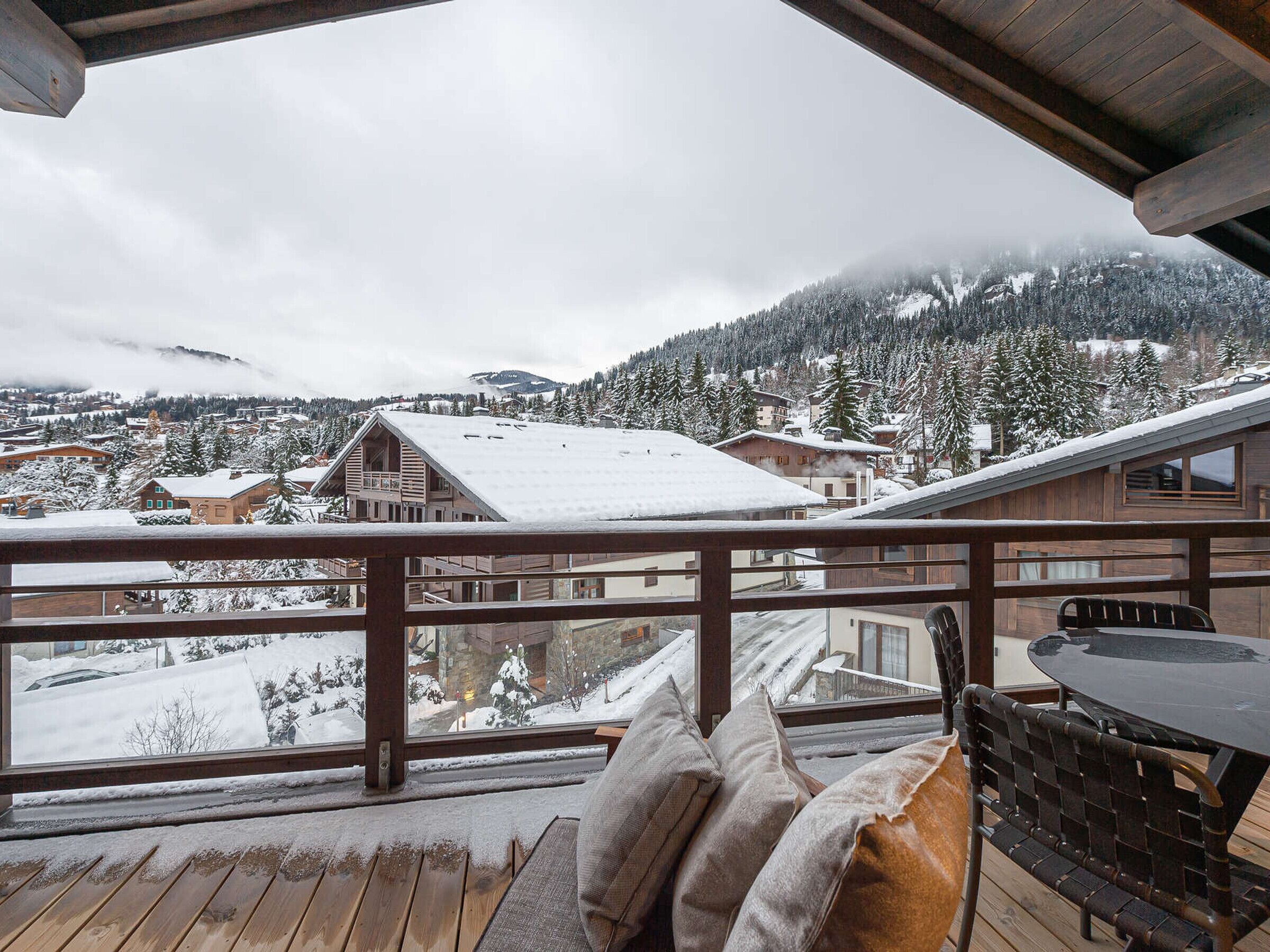 A wooden deck with a view of a snowy mountain town.