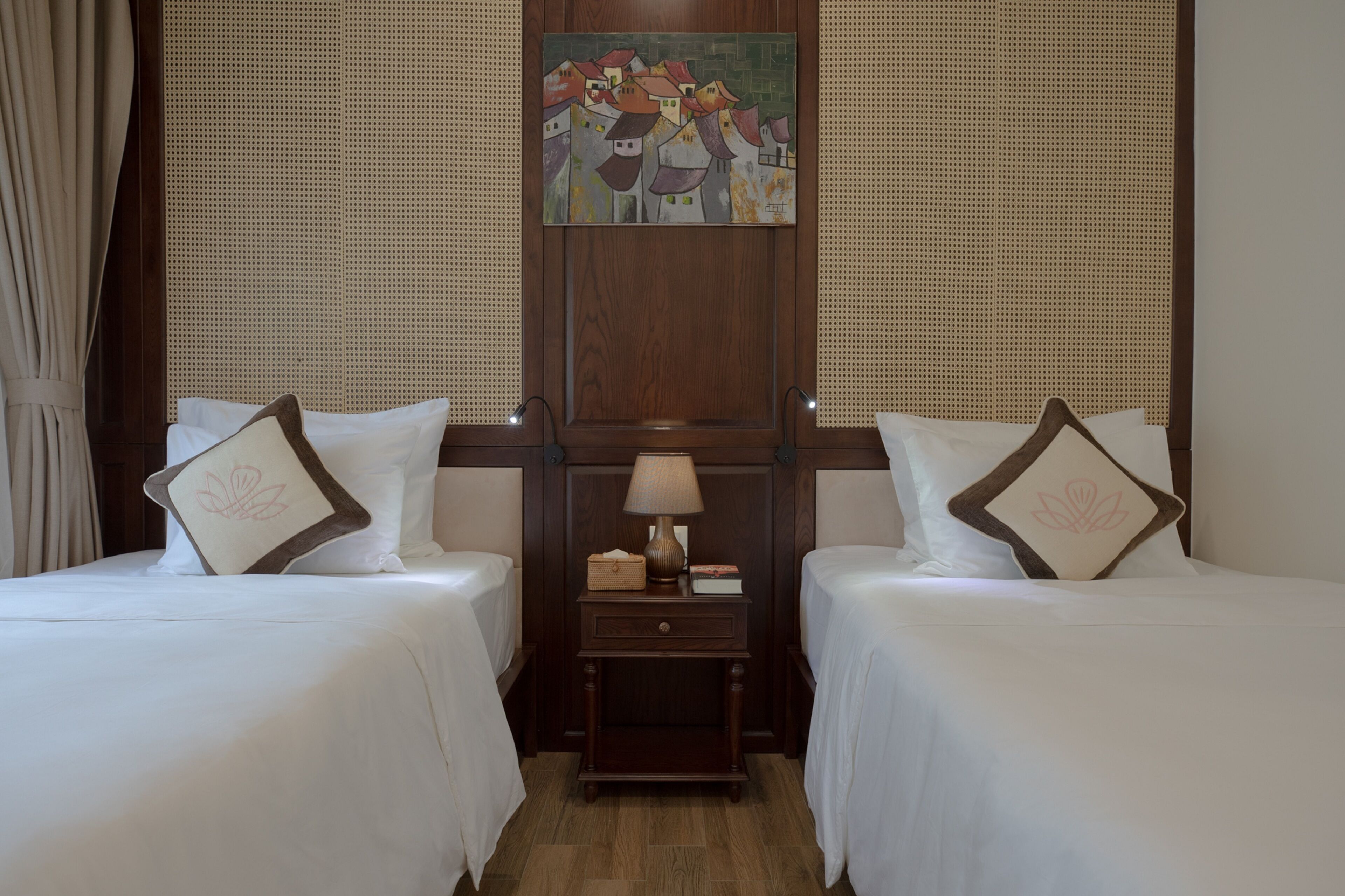 A hotel room with two beds, a nightstand with a lamp, and a painting on the wall.