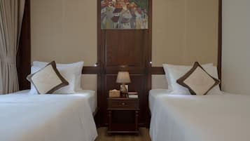A hotel room with two beds, a nightstand with a lamp, and a painting on the wall.