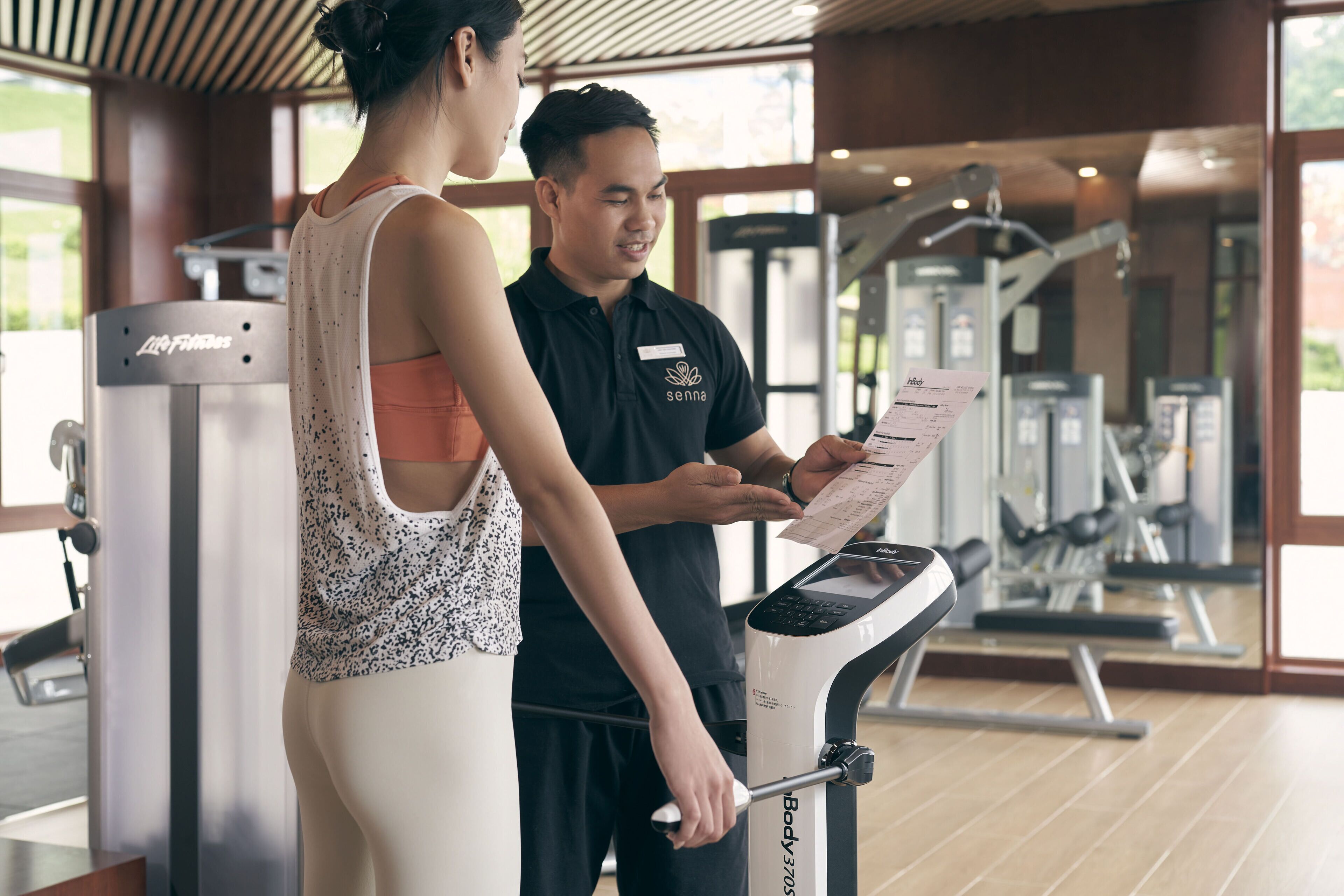 A gym with exercise equipment and a person using a stationary bike.