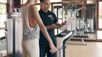 A gym with exercise equipment and a person using a stationary bike.