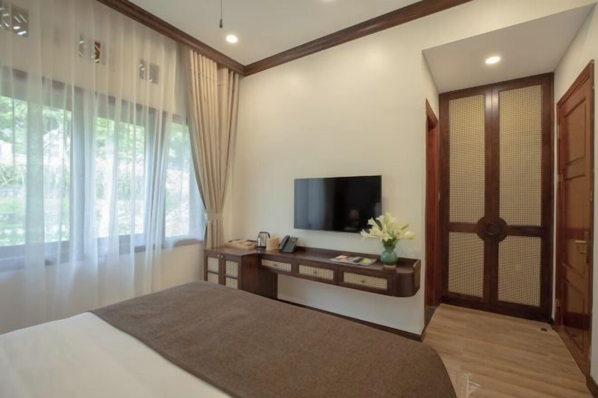 Un dormitorio con cama, televisión, escritorio y puerta corredera tradicional japonesa.