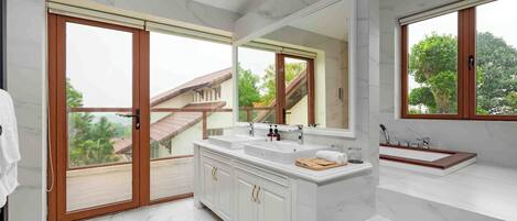 Un baño moderno con un espejo grande, dos lavamanos y una bañera.