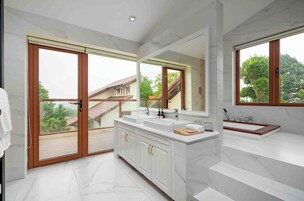 Uma casa de banho moderna com um espelho grande, duas pias e uma banheira.