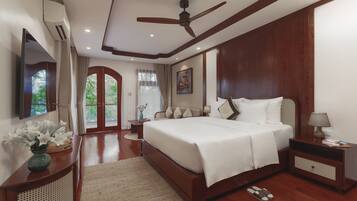 A spacious bedroom with a large bed, a ceiling fan, a TV, and a view of the outdoors.