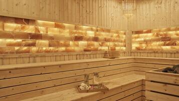 Un sauna en bois avec des bancs, un plateau contenant des serviettes et une bouteille.