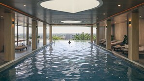 Uma grande piscina interior com vista para a paisagem urbana, rodeada por áreas de lazer e arquitetura moderna.