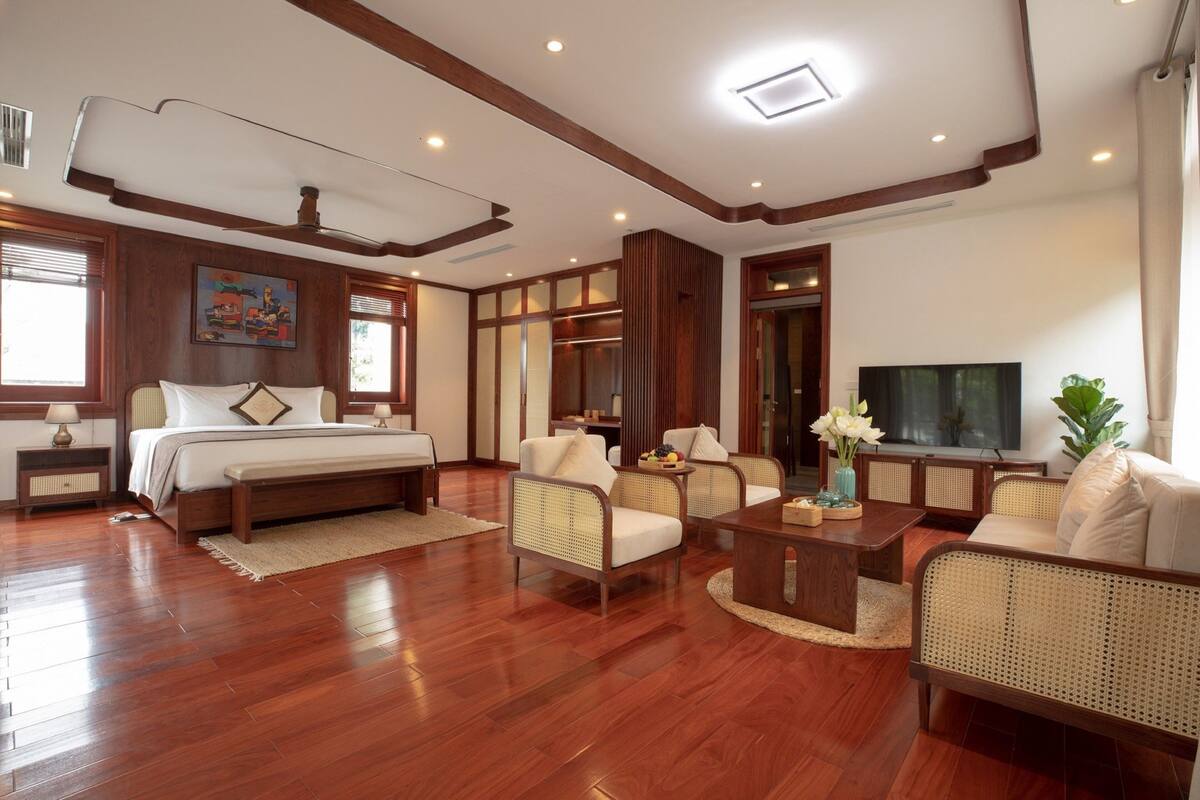 A spacious living room with a large bed, two sofas, a coffee table, and a TV.