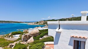 Un bâtiment situé sur la côte, offrant une vue sur la mer, un paysage rocheux et une végétation luxuriante.