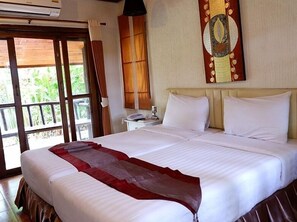 Quarto de hotel com uma cama grande, mesa de cabeceira com telefone e janela com cortinas.