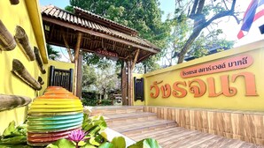 Perinteinen thaimaalainen rakennus, jossa on puinen sisäänkäynti ja thaikielinen kyltti.