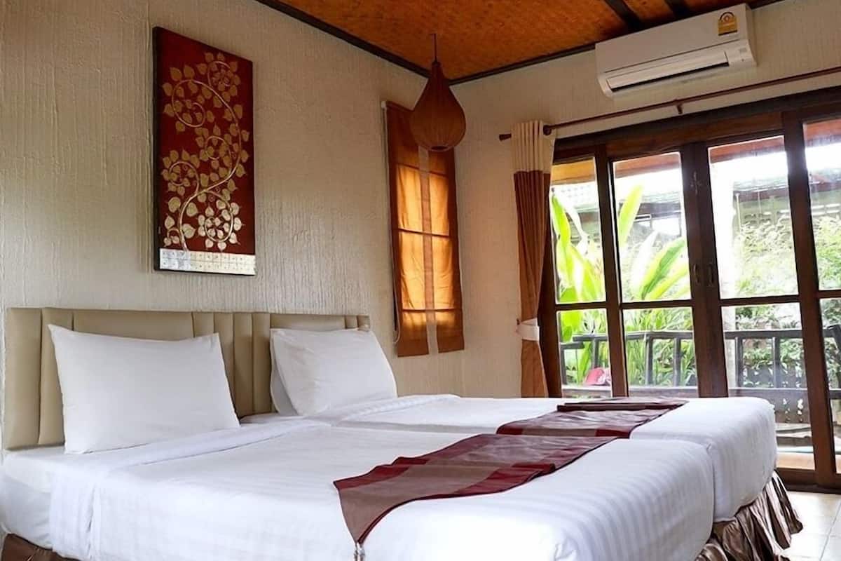 Une chambre d’hôtel avec deux lits, une grande fenêtre avec des rideaux, un ventilateur de plafond et un appareil de climatisation.