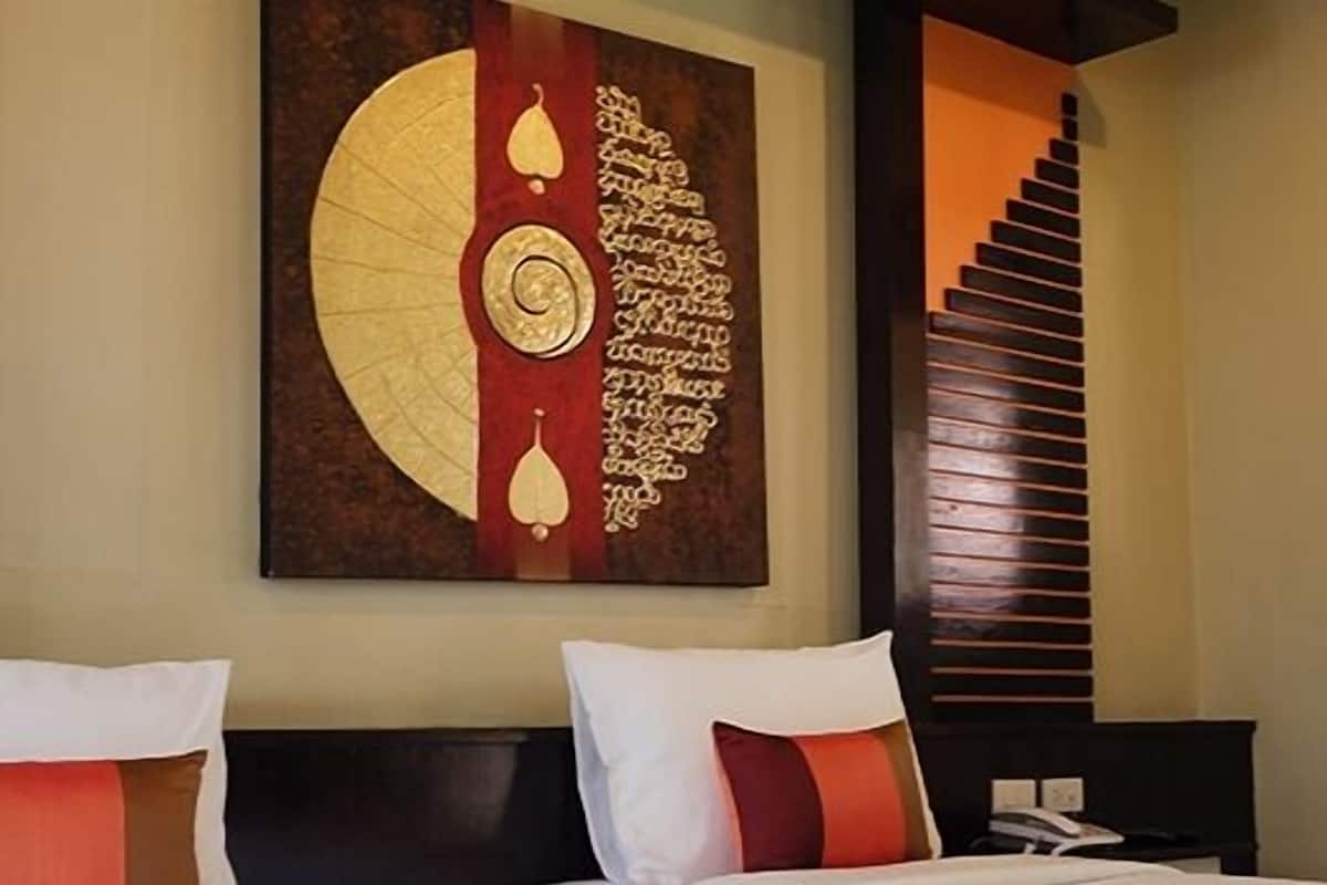 Une chambre d’hôtel avec un lit, deux oreillers, une œuvre d’art murale, une fenêtre avec des stores et un escalier.