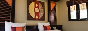 Quarto de hotel com cama, duas almofadas, uma obra de arte na parede, janela com persianas e uma escada.