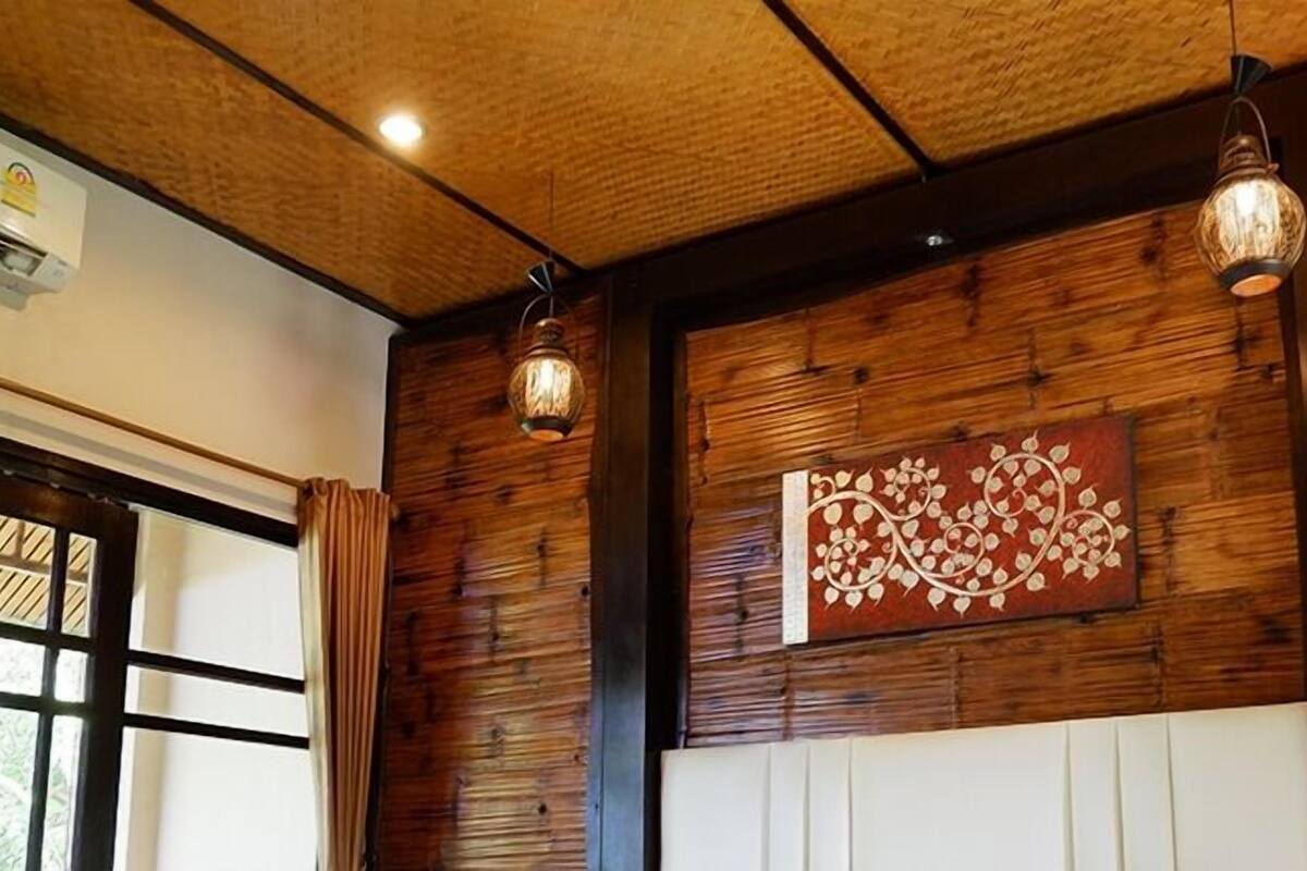 Une pièce aux murs recouverts de panneaux de bois, ornée d’un élément décoratif mural et dotée de deux luminaires suspendus.