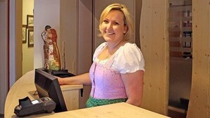 A person standing at a wooden desk with a computer monitor, a telephone, and a keyboard. - Brauhotel & Gasthof GROSCH (Roedental)