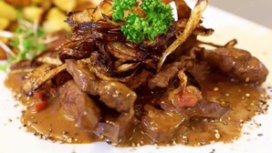A dish of beef with caramelized onions and a garnish of parsley, served on a white plate. - Brauhotel & Gasthof GROSCH (Roedental)