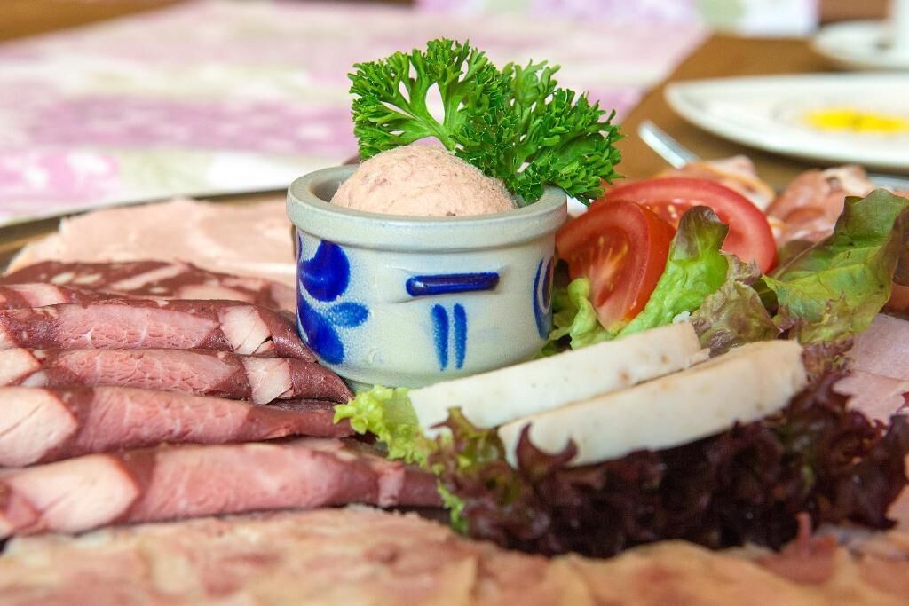 Ein Teller mit Aufschnitt, eine Dip-Schale und frisches Gemüse.