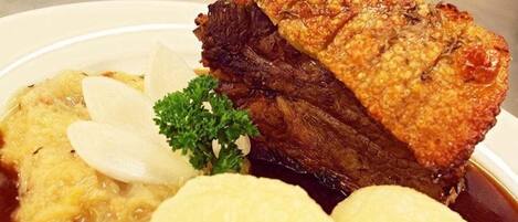 A plate with a piece of meat, boiled potatoes, and a garnish.