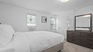 Un dormitorio con cama, cómoda y un espejo grande.