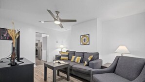 Una sala de estar moderna con un sofá gris, una mesa de centro y un ventilador de techo.