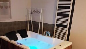 Une salle de bain moderne avec une baignoire sur pieds, un banc et un porte-serviettes.