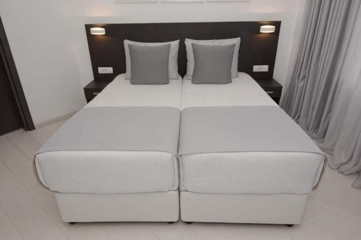 Un lit double avec deux oreillers, une table de chevet et un luminaire fixé au mur.
