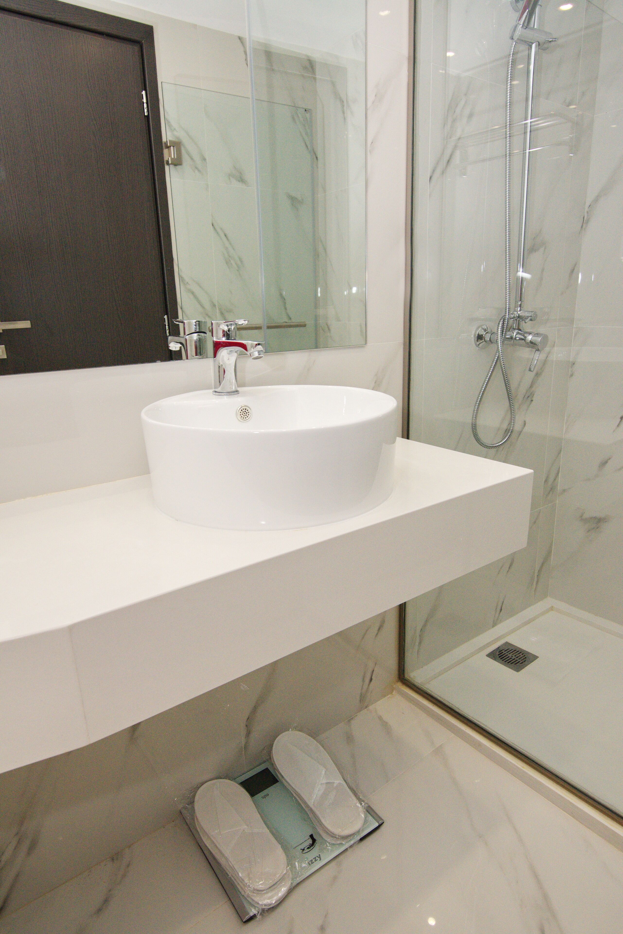 Une salle de bain avec un lavabo blanc, un miroir et une douche à parois de verre.